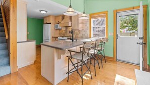 Une cuisine dotée d’un îlot central, de meubles en bois, d’un réfrigérateur et d’un coin repas avec des chaises.