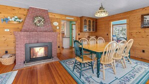 Un intérieur de chalet chaleureux avec une cheminée en briques, une table à manger en bois et des chaises.