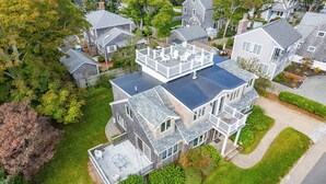 Une maison à plusieurs étages dotée d’une grande terrasse et d’un patio couvert.