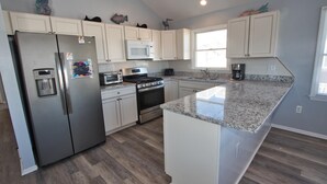 A modern kitchen with stainless steel appliances, white cabinetry, and a granite countertop.