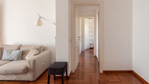 A room with a sofa, a small table, a lamp, and a hallway leading to another room. - Vittorio Panoramic Apartment (Roma)