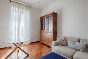 Une pièce avec une table à plateau en verre, un meuble en bois et un canapé beige.