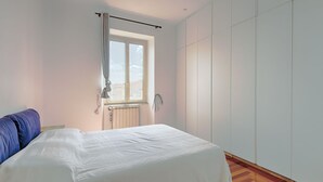 A bedroom with a bed, a window, a radiator, and a wardrobe. - Vittorio Panoramic Apartment (Roma)