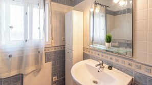 A bathroom with a sink, mirror, and shower.