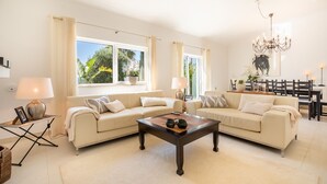 A spacious living room with two beige sofas, a wooden coffee table, and a chandelier. - Quinta Felicidade, 4 bedroom holiday villa with private pool (Lagos)