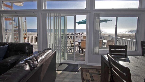 Ein geräumiger Balkon mit Blick auf den Strand, ein Ledersofa und ein Holztisch.