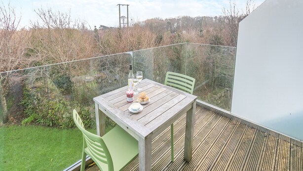 A wooden deck with a table and chairs, a bottle of white wine, and a glass of wine. - 1 bedroom accommodation in Carbis Bay, near St Ives (Carbis Bay, near St Ives)