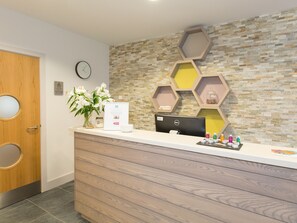 A reception desk with a computer, a clock, and a wall with hexagonal shelves. - 1 bedroom accommodation in Carbis Bay, near St Ives (Carbis Bay, near St Ives)