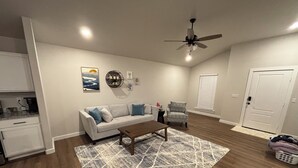 Un salon comprenant un canapé, une table basse, un tapis à motifs et un ventilateur de plafond.