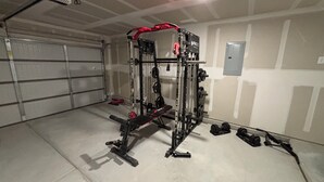 Une salle de sport équipée d’un support à squats, de bancs et de poids.