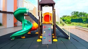 Une aire de jeux avec un toboggan vert, un mur d’escalade et une petite cabane décorée de motifs de papillons.