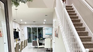 A spacious hallway with a carpeted floor leading to a staircase with white balusters and a beige carpet. - Our stunning luxury villa, complete with a heated pool, a relaxing hot tub, (Davenport)
