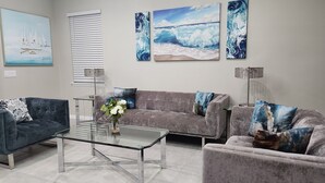 A living room with a glass coffee table, two sofas, and three paintings on the wall. - Our stunning luxury villa, complete with a heated pool, a relaxing hot tub, (Davenport)