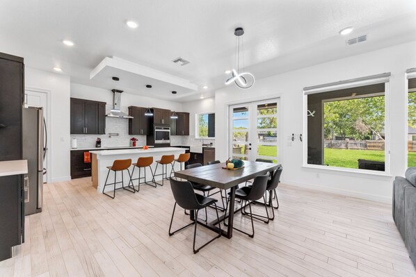 Una cocina moderna con una isla central, armarios oscuros y una zona de comedor con sillas.