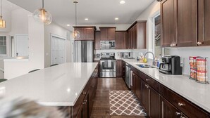 A modern kitchen with a large island, stainless steel appliances, and dark wood cabinets. - Luxury Escape in East Wenatchee (East Wenatchee)