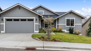 A two-story house with a garage, a small front yard with a tree, and a clear blue sky. - Luxury Escape in East Wenatchee (East Wenatchee)