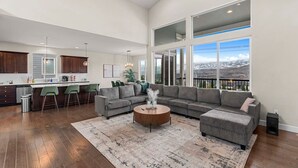 A spacious living area with a gray sectional sofa, a round coffee table, and a large window offering a view of a snowy landscape. - Luxury Escape in East Wenatchee (East Wenatchee)