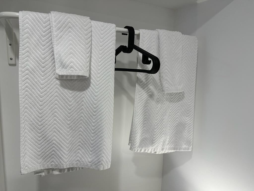 A bathroom with two white towels hanging on a black towel rack.