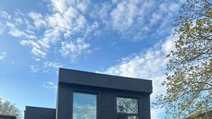 Een modern huis met twee verdiepingen, een garage, een groot raam op de bovenverdieping en een gevel van baksteen.