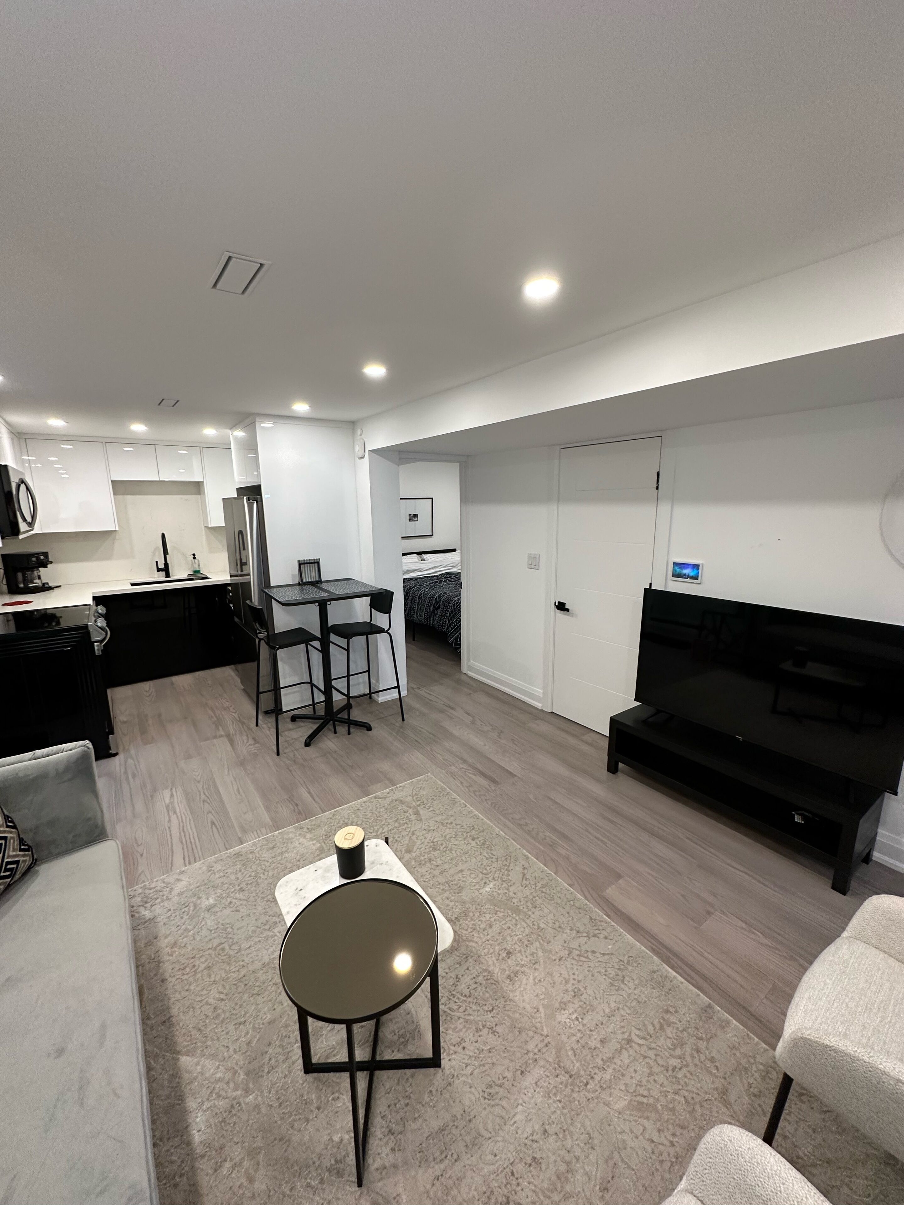 A modern living room with a sofa, a coffee table, a TV, and a dining area with chairs and a table.