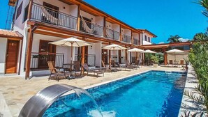 A two-story hotel with a swimming pool, outdoor seating, and a covered patio area. - Pousada Mirante do Sol (Paraty)