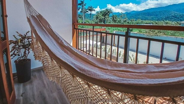 A hammock on a balcony with a view of a lush landscape and mountains. - Pousada Mirante do Sol (Paraty)