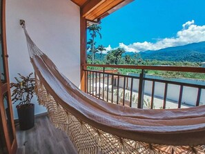 A hammock on a balcony with a view of a lush landscape and mountains. - Pousada Mirante do Sol (Paraty)