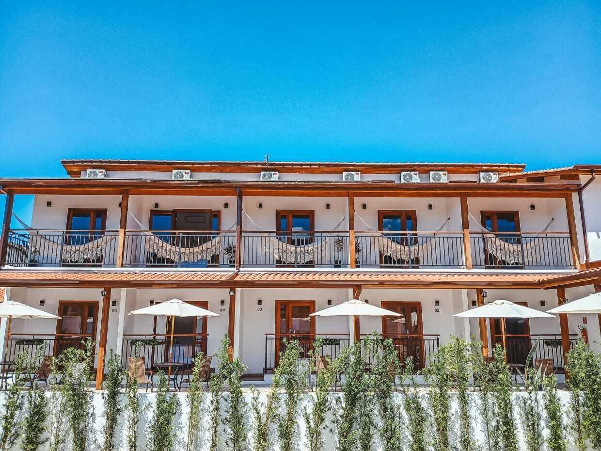 A multi-story hotel with balconies, outdoor seating, and air conditioning units.
