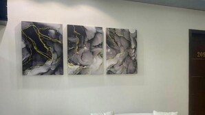 A white sofa with cushions in a room with three abstract paintings on the wall. - Scarlett Apartments (Monrovia)