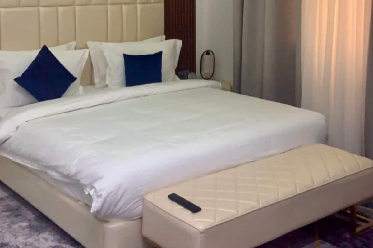 Une chambre d’hôtel avec un grand lit, une table de chevet, une télécommande et une moquette à rayures.