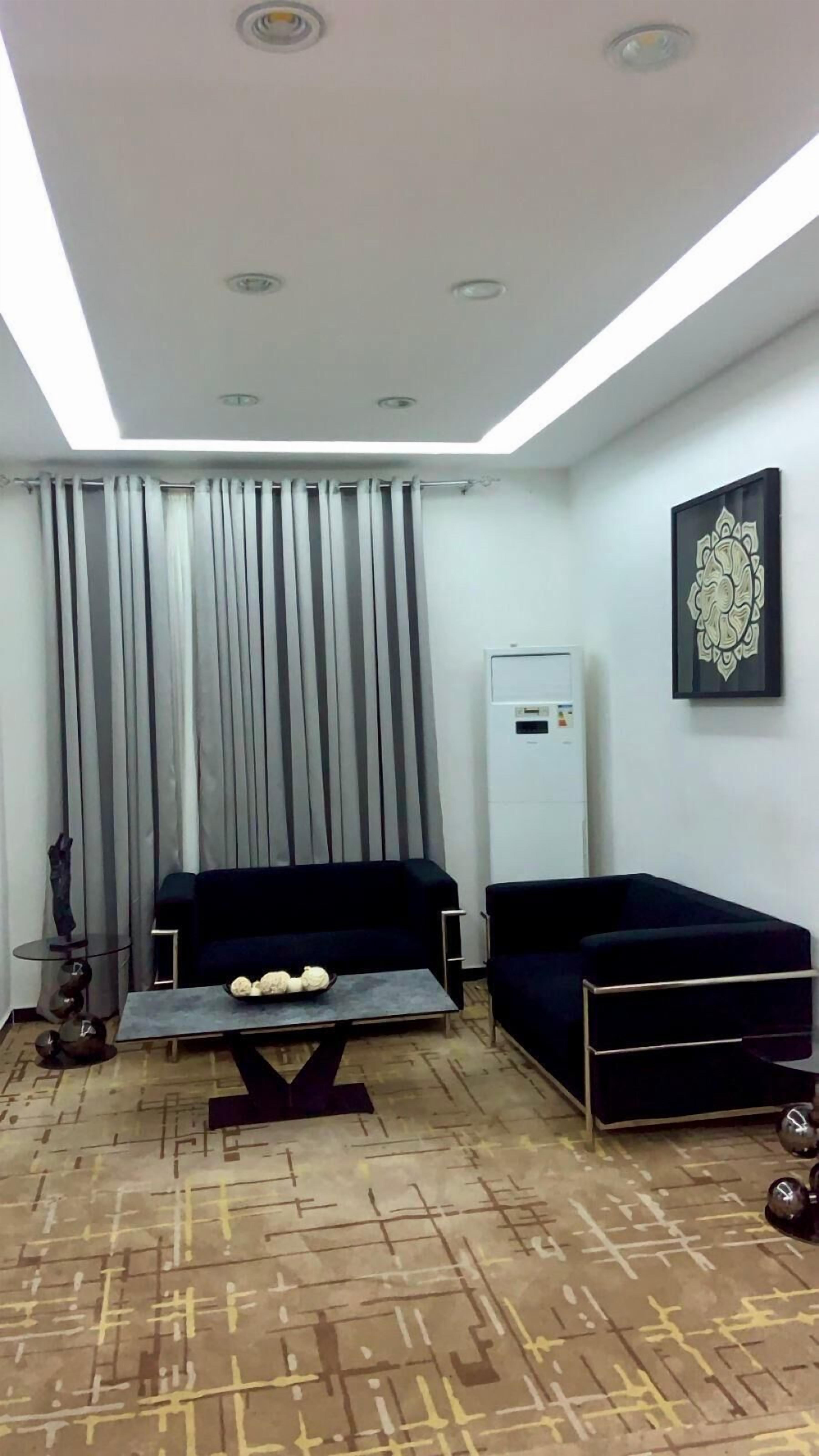 A modern living room with a sofa, a coffee table, a decorative wall piece, and a water dispenser.