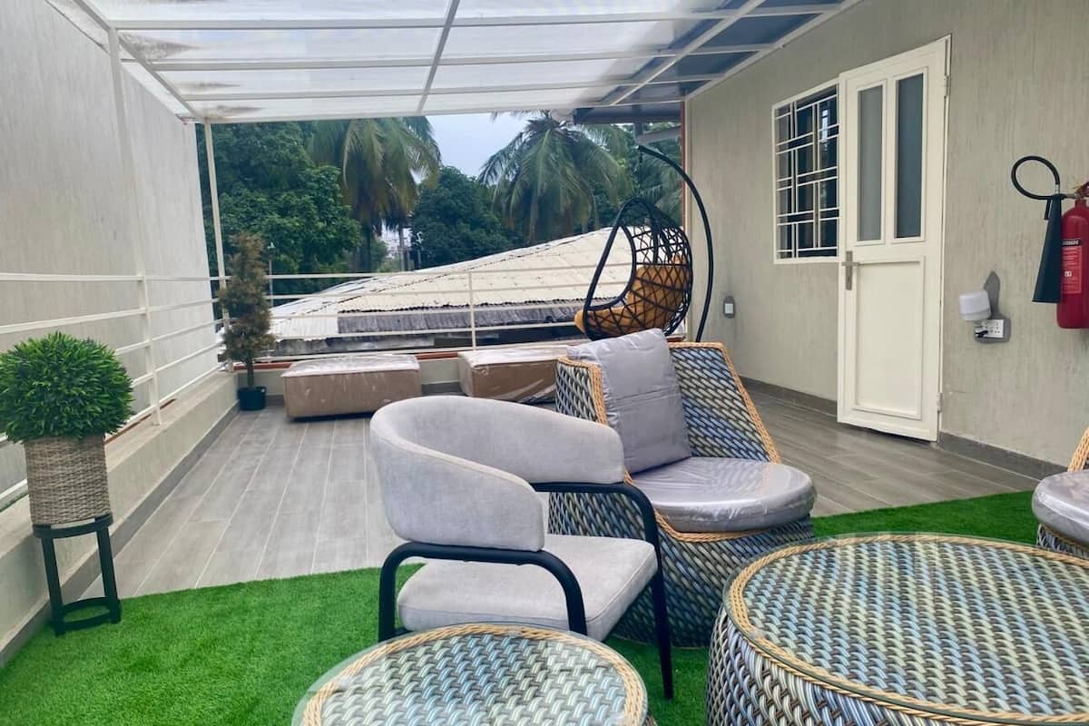 Un espace extérieur aménagé, abrité et doté de mobilier en osier, d’un canapé confortable et d’une petite table ronde.