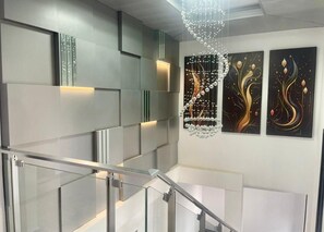 A modern staircase with glass railings and abstract wall art. - Scarlett Apartments (Monrovia)