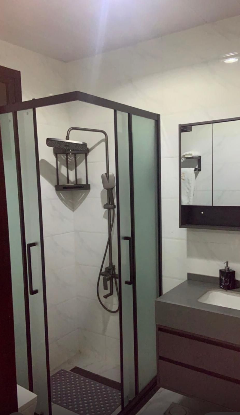 Un baño moderno con ducha de vidrio, tocador con espejo e inodoro.