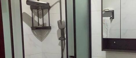 A modern bathroom with a glass-enclosed shower, a vanity with a mirror, and a toilet.