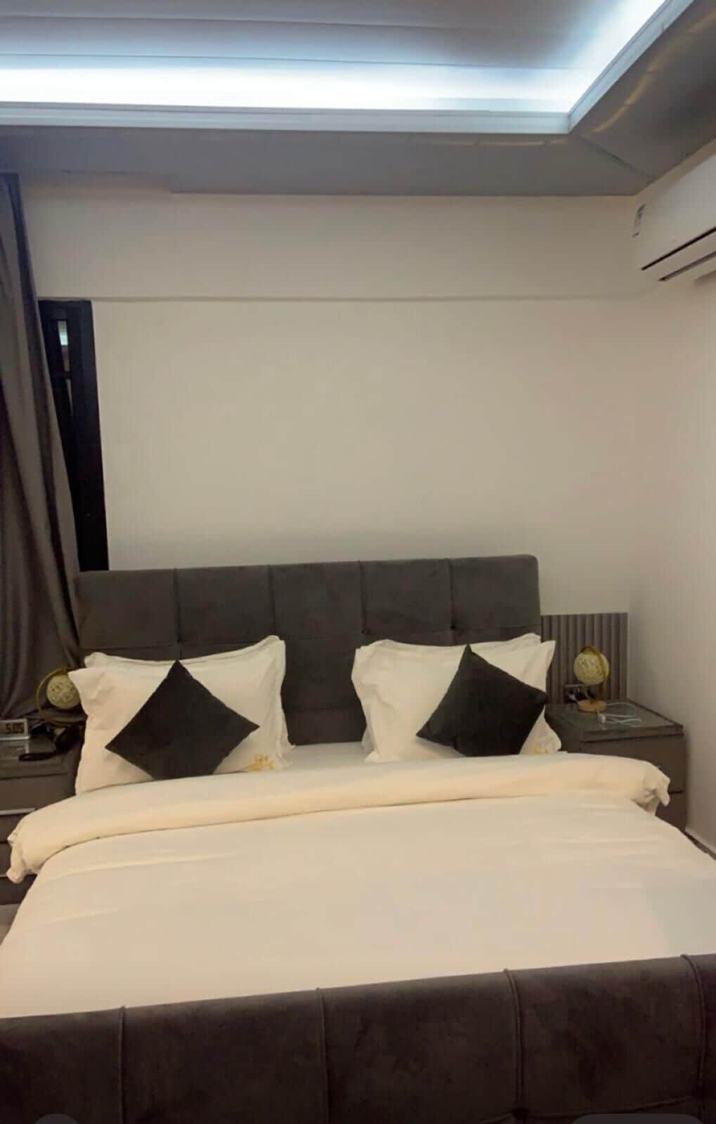 A modern hotel room with a large bed, a headboard, and a nightstand with a lamp.