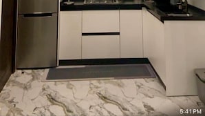 A modern kitchen with white cabinets, a stainless steel refrigerator, a microwave, and a black countertop. - Scarlett Apartments (Monrovia)
