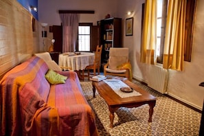 A cozy living room with a sofa, a wooden coffee table, a bookshelf, and a dining table.