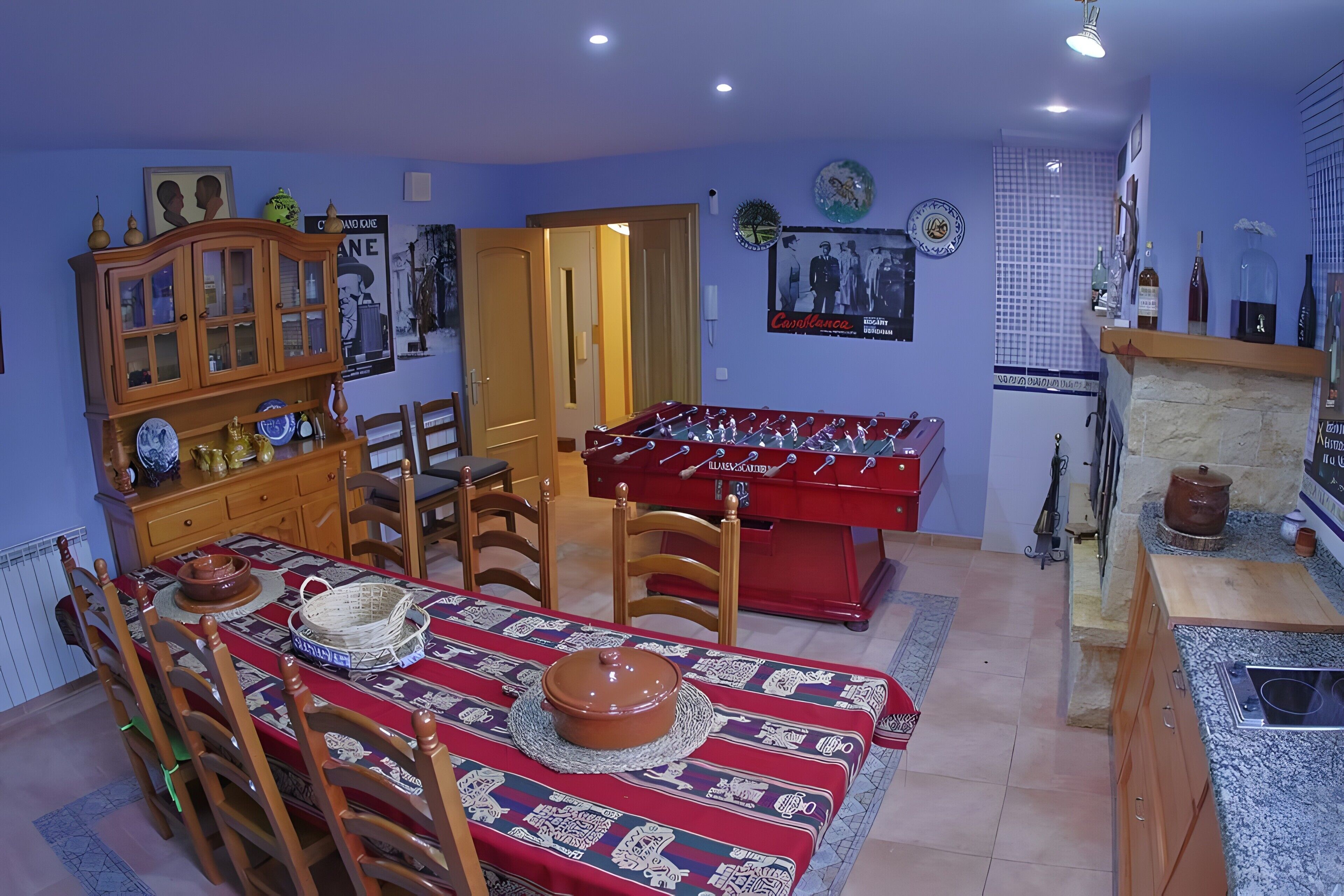 Un coin repas avec un baby-foot, des meubles en bois et une nappe rouge.