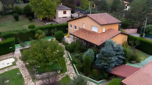 A two-story house with a tiled roof, surrounded by a well-maintained garden with various plants and a stone pathway.