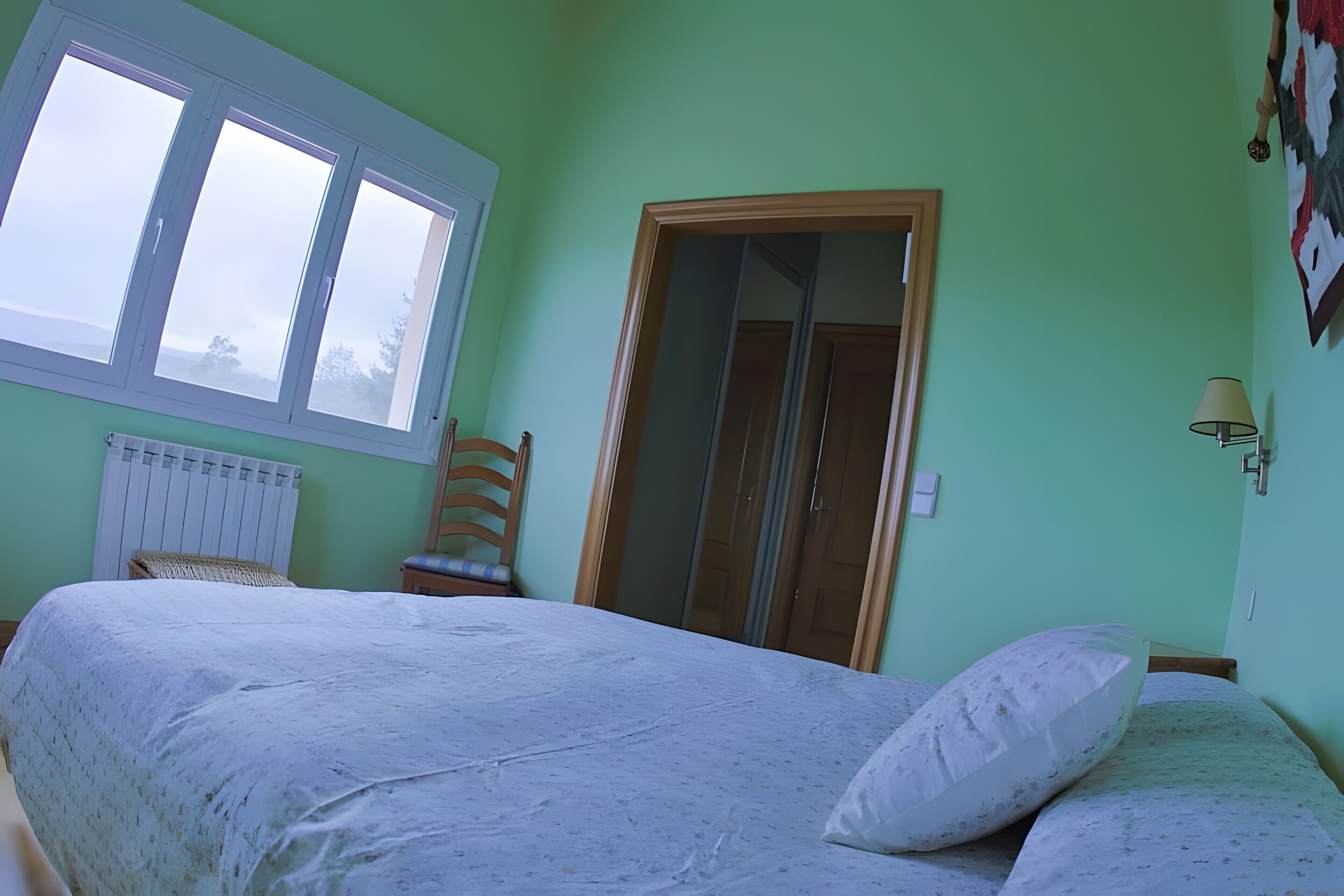 Una camera da letto con un letto, una finestra, un termosifone, un armadio e una sedia.