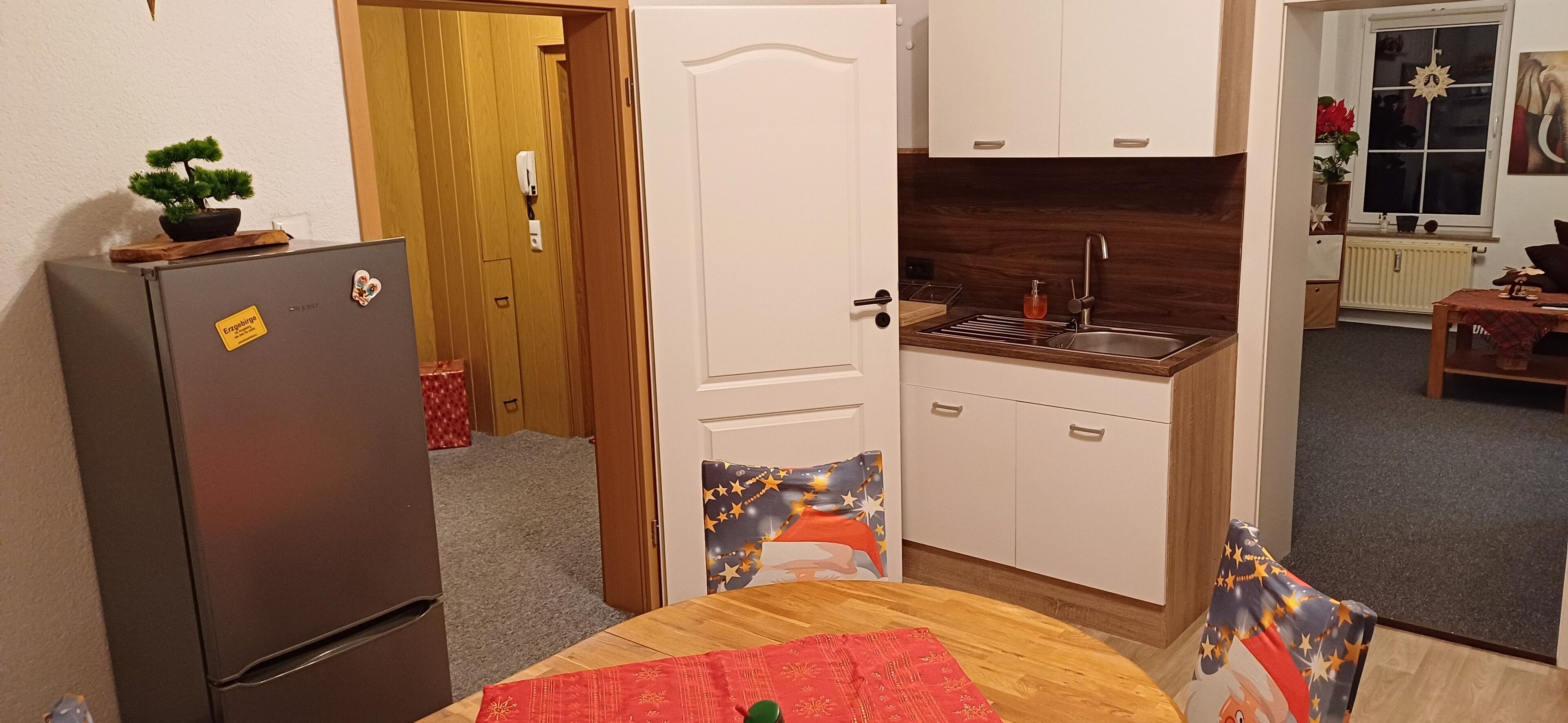 A compact kitchen with a refrigerator, a sink, and cabinets.