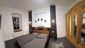 A bedroom with a bed, a wardrobe, a window, and a radiator.