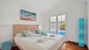 Una camera da letto con un letto grande, un quadro, una finestra con vista e un oggetto cilindrico blu.