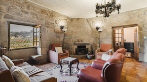 Una stanza con pareti in pietra, un camino, divani in pelle, un tavolino da caffè e un lampadario.