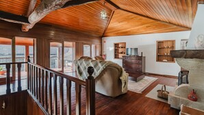 Un'ampia zona giorno con pavimento in legno, soffitto alto e grandi finestre.