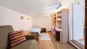 A bedroom with a bed, a sofa, a desk, and a bookshelf.