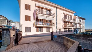 A multi-story building with balconies, a paved courtyard, and a gated entrance.