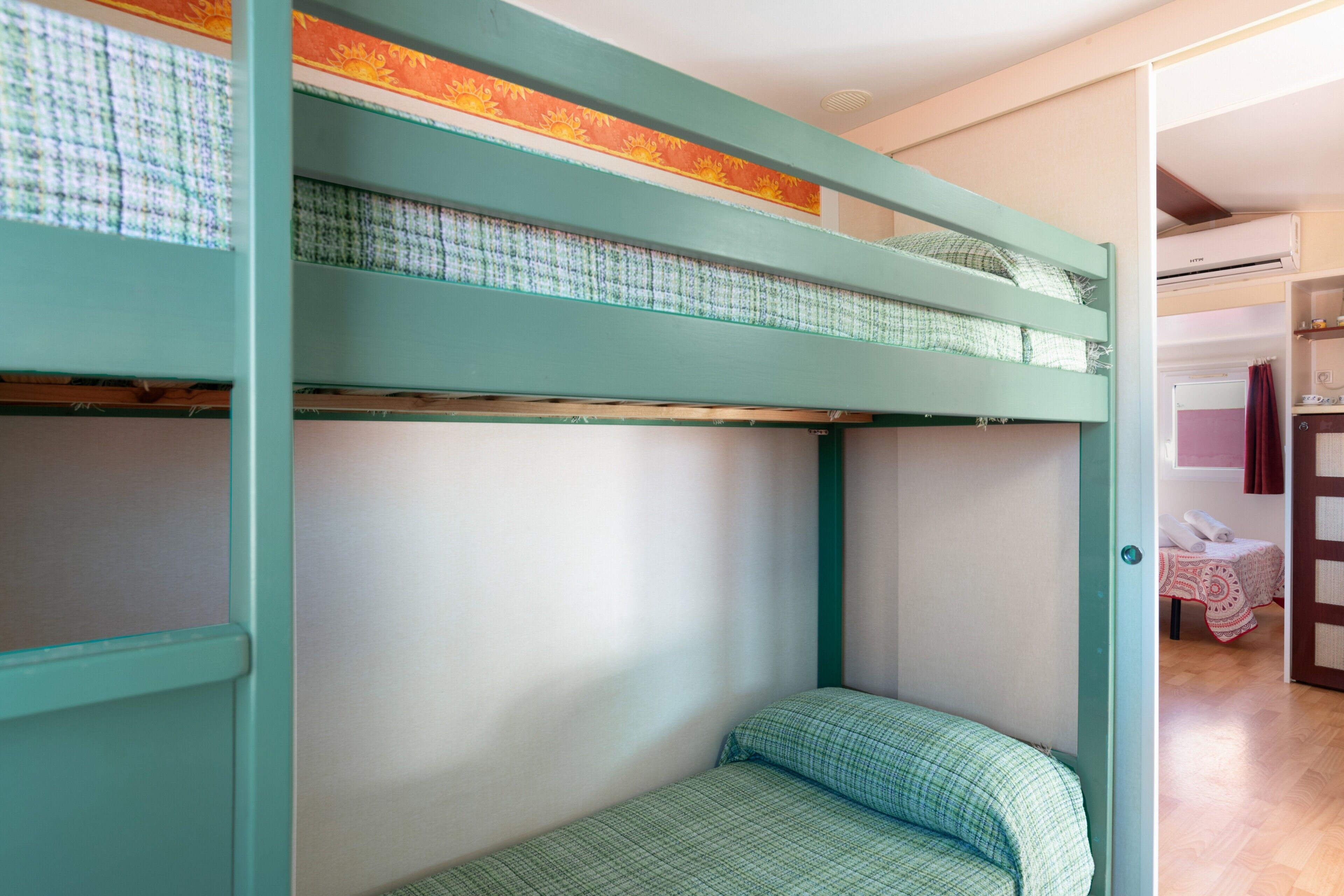 Un lit superposé avec un matelas à carreaux et un lit inférieur avec un oreiller.