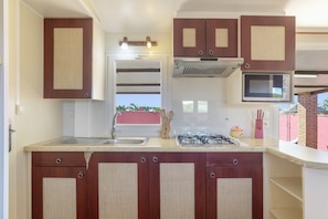A kitchen with wooden cabinets, a stainless steel sink, a microwave, and a gas stove.